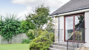 A residential house with a front porch, steps leading to a door, a small garden, and a wooden fence. - 4 bedroom accommodation in Spittalfield, nr Dunkeld (Spittalfield, nr Dunkeld)