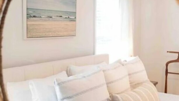 Ein Schlafzimmer mit einem Bett, Kissen, einem Fenster und einem Bild an der Wand.