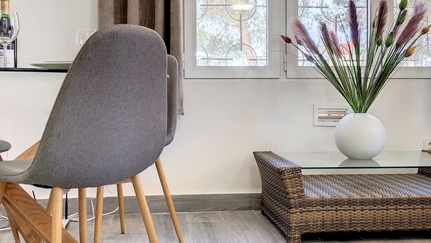 A modern living room with a grey upholstered chair, a wicker sofa, a glass coffee table, and a vase with pampas grass. - Villa with private pool, close to the beach (El Carmoli)