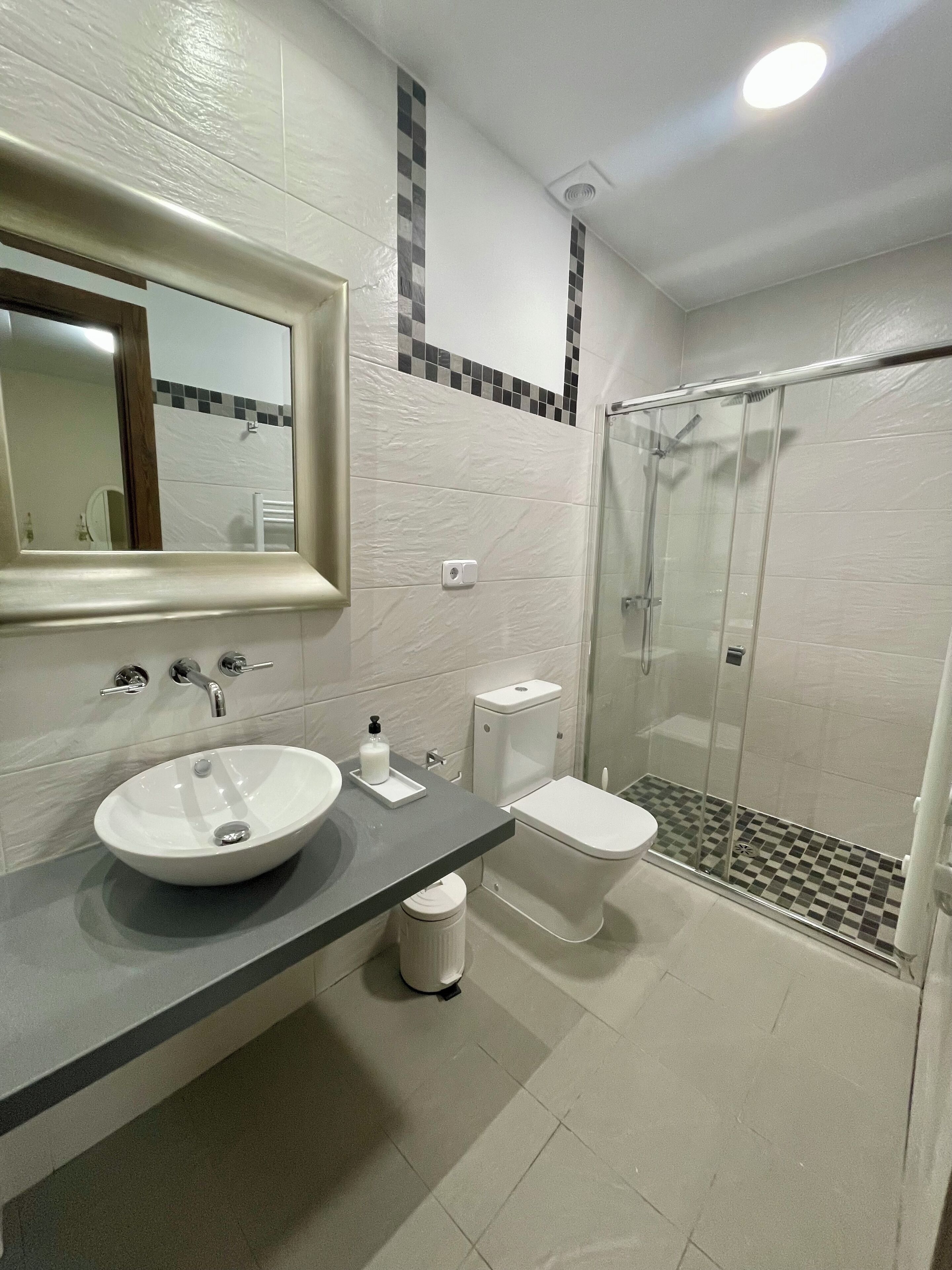 Een bad/douchecombinatie, een haardroger, handdoeken, zeep