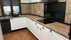 Une cuisine avec des meubles blancs, une cuisinière noire et un dosseret carrelé.
