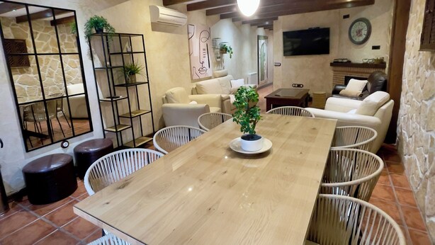 Un coin repas avec une table en bois entourée de chaises en osier, une plante en pot et un luminaire moderne au plafond.