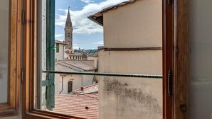 A window with a view of a building with a tower and red-tiled roofs. - Lezioso "VIP", 2 bedrooms in the heart of Florence (Firenze)