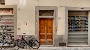 A street view with a wooden double door, a metal shutter, and bicycles parked in front. - Lezioso "VIP", 2 bedrooms in the heart of Florence (Firenze)