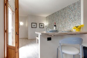 Uma cozinha com bancada de madeira, uma cadeira e parede com padrão floral.