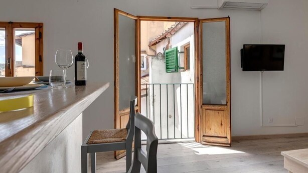 A kitchen with a wooden counter, a chair, a wine bottle, and a television on the wall. - Lezioso "VIP", 2 bedrooms in the heart of Florence (Firenze)