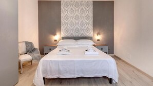 A modern bedroom with a large bed, two bedside tables, a chair, and a patterned wall. - Lezioso "VIP", 2 bedrooms in the heart of Florence (Firenze)