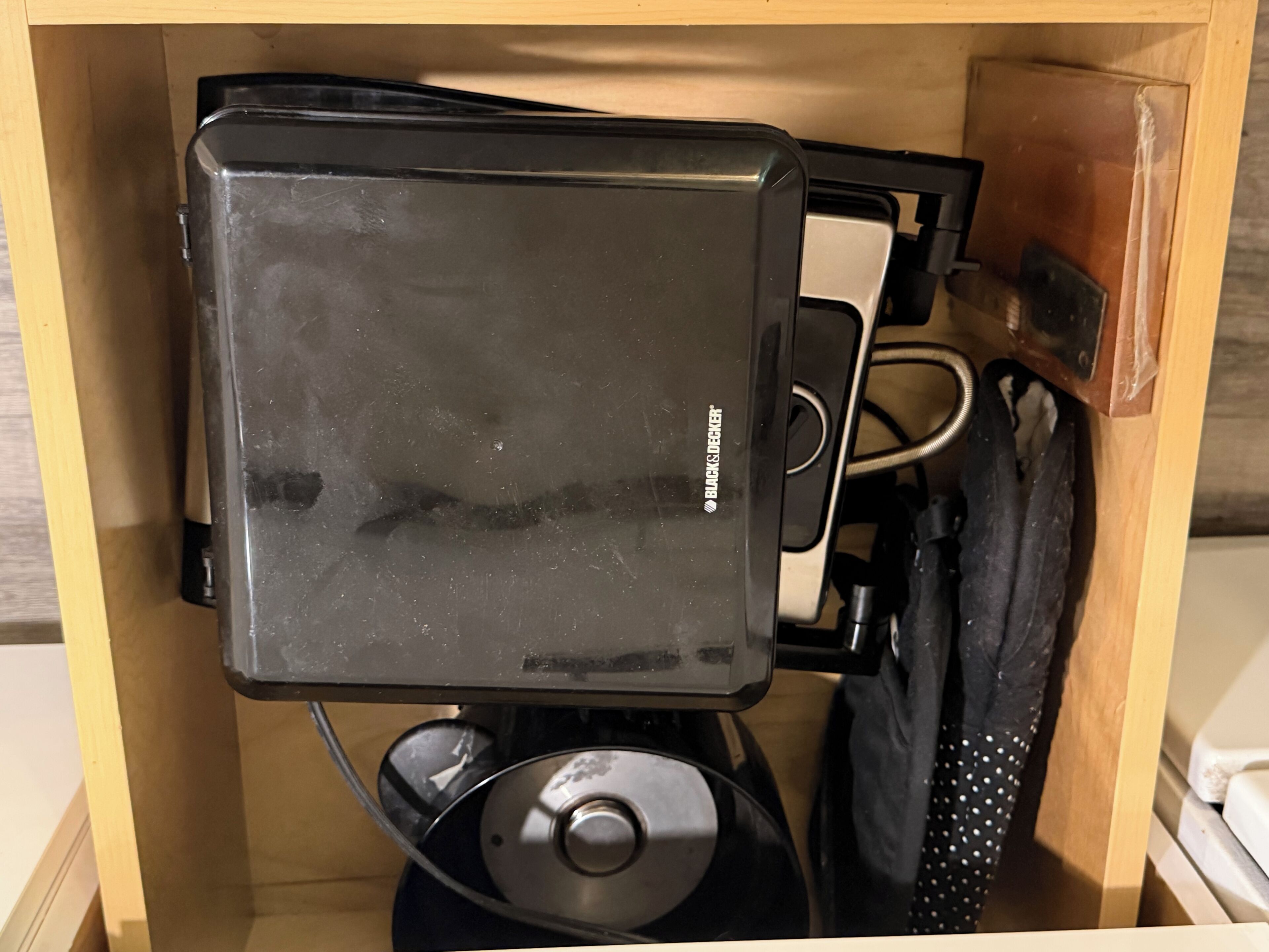Un calaix amb un aparell Black & Decker, un cable d'alimentació i una bossa negra.