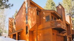 Una cabaña de madera con garaje, ventanas amplias y un balcón.