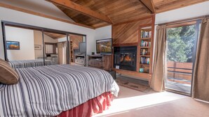Un dormitorio con cama, televisión, chimenea y estantería.