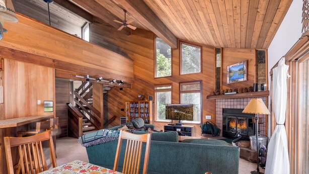 Interior acogedor de una cabaña con chimenea, paredes de madera, una escalera y una zona de estar confortable.