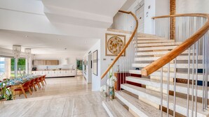 A spacious kitchen with modern appliances, a dining area with a large table and chairs, and a curved staircase with wooden steps and metal railings. - Adriatic Beach House (Vrbica)