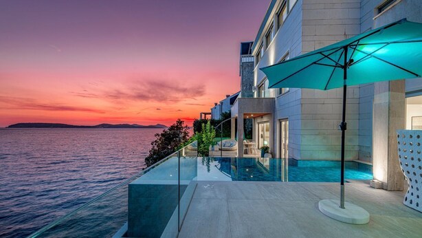 A modern hotel with a glass infinity pool overlooking the sea, a private outdoor seating area, and a view of the sunset. - Adriatic Beach House (Vrbica)