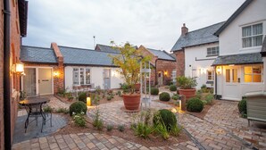 A courtyard with brick pathways, potted plants, and outdoor seating. - The Lion at Malpas (Malpas)