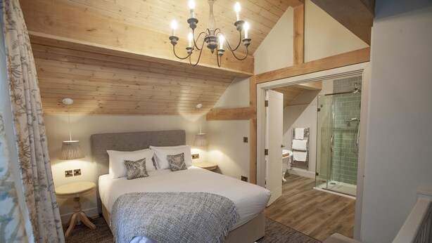 A bedroom with a large bed, a bedside table, a lamp, and a chandelier. - The Lion at Malpas (Malpas)