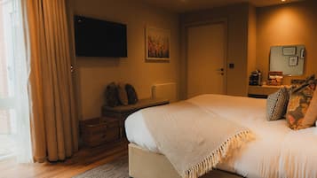 A bedroom with a bed, a television on the wall, a suitcase, and a window with curtains.