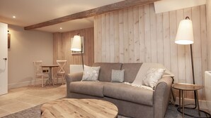 A cozy living room with a sofa, a round wooden coffee table, and two floor lamps. - The Lion at Malpas (Malpas)