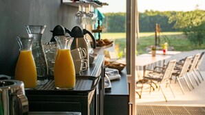 Eine Bar mit einer Kaffeemaschine, Gläsern und Blick ins Freie.
