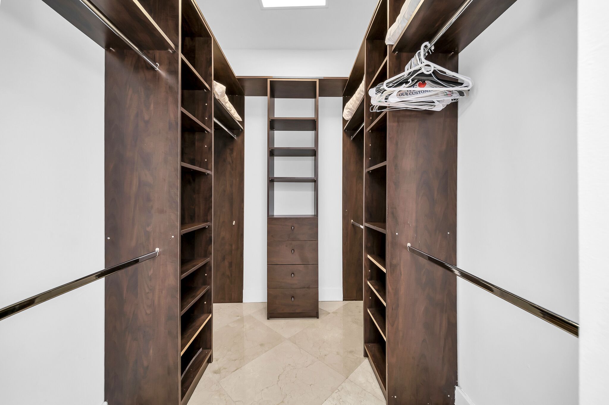 A walk-in closet with wooden shelving and a central sliding ladder.