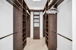 A walk-in closet with wooden shelving and a central sliding ladder.