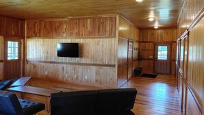 Ein Zimmer mit Holzwänden, einem Wand-Fernseher, einer Bank und einem Tisch.