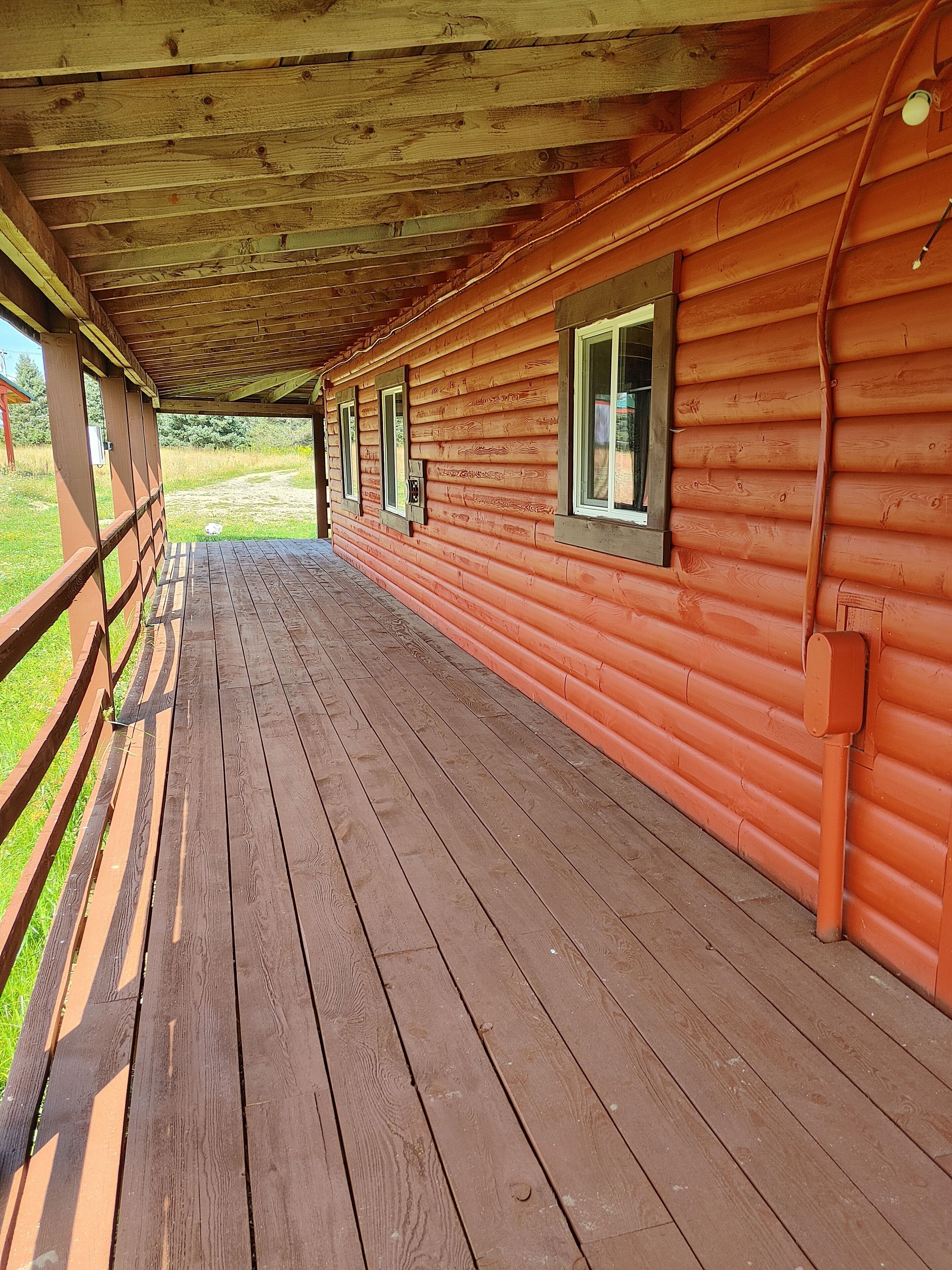 A wooden cabin with a covered porch and windows.