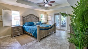A bedroom with a bed, nightstands, a ceiling fan, and a large window.