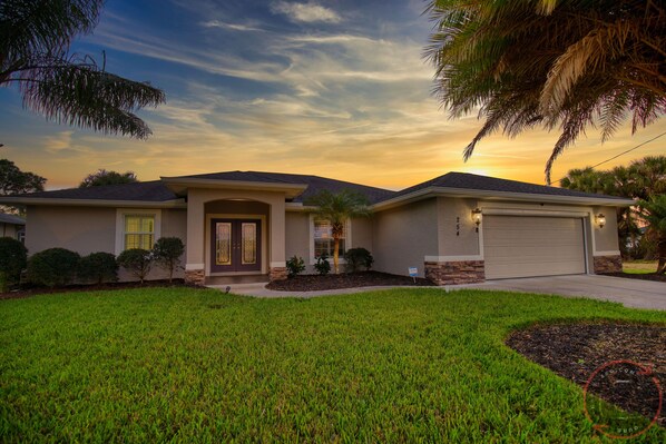 A residential house with a well-maintained lawn, a garage, and a driveway.