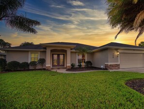 A residential house with a well-maintained lawn, a garage, and a driveway.