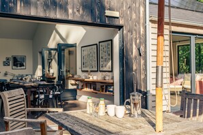 An outdoor dining area with wooden furniture, a table with milk bottles and cups, and a coffee pot. - Missy's House in the Woods - Harringworth , Northamptonshire (Harringworth)