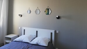 Un dormitorio con una cama, una mesita de noche y tres luces fijadas a la pared.