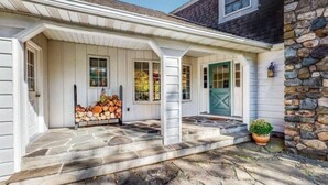 A house with a stone porch, white siding, and a green door. - Birch Hill - Luxury Mountain Retreat (Windham)