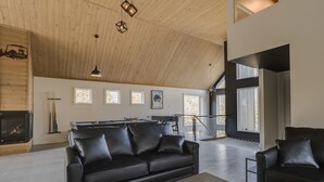 Un vaste espace de vie doté d’un haut plafond, d’une cheminée, d’une table de billard et d’un escalier menant à un niveau supérieur.