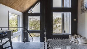Une chambre moderne avec de grandes fenêtres, un lit en mezzanine et une table de jeux.