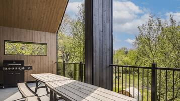Enjoy al fresco dining on the patio with a barbecue grill and seating area overlooking a lush landscape.