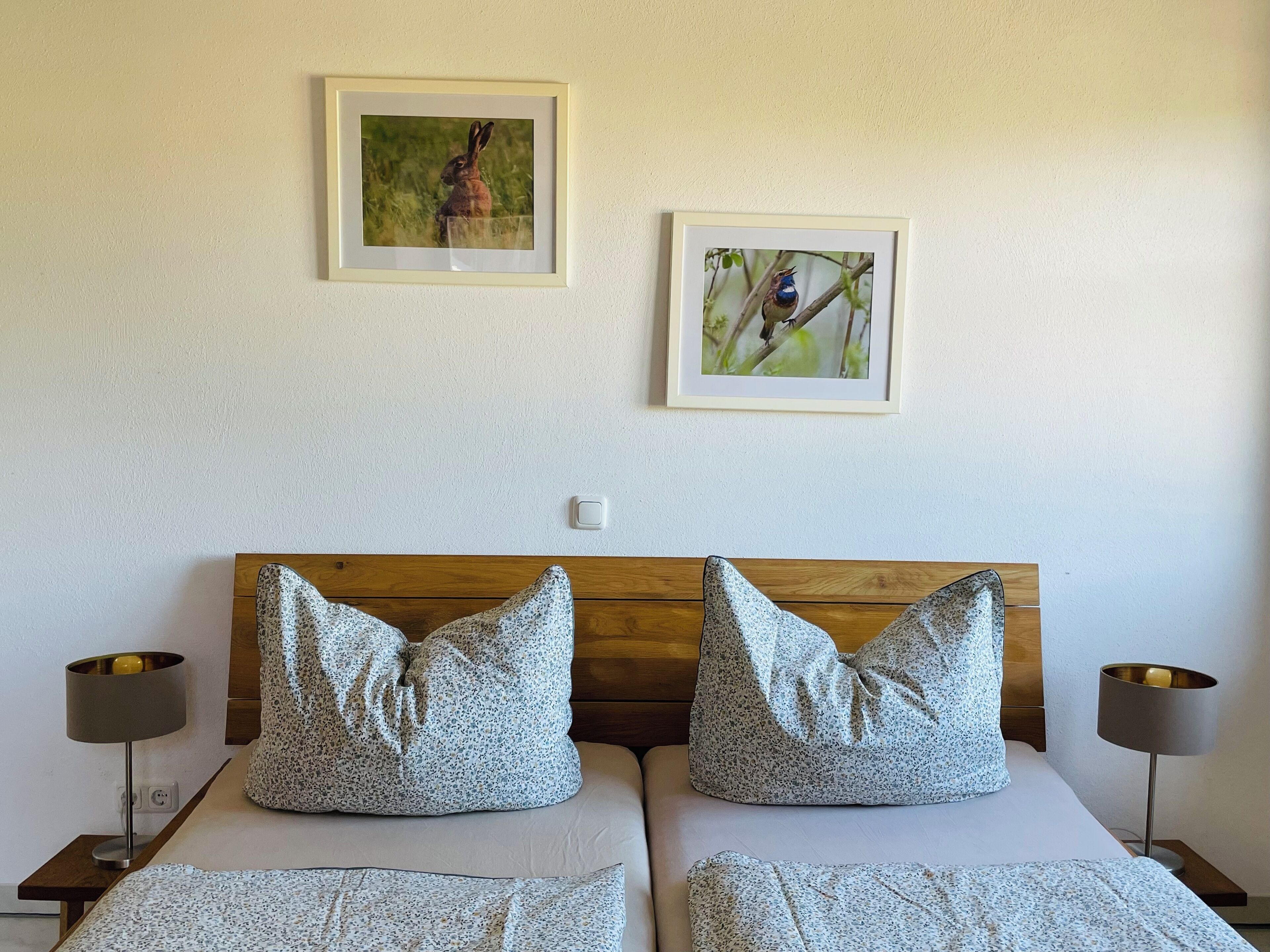 A double bed with two pillows, a wooden headboard, and two bedside tables with lamps.