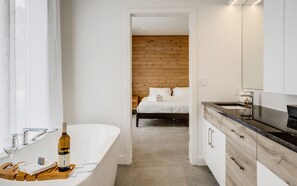A modern bathroom with a freestanding bathtub, a sink, and a mirror.