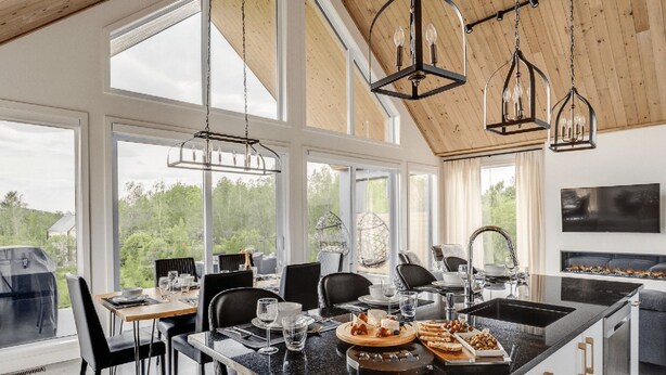 A modern kitchen with large windows, a dining area, and a view of the outdoors. - The Experience SÔ Lodge (SHEFFORD)