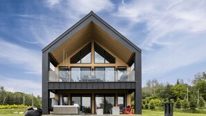 A modern two-story house with a prominent triangular roof, large windows, and a balcony. - The Experience SÔ Lodge (SHEFFORD)