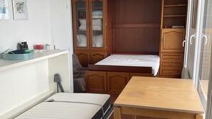 Une petite pièce comprenant un lit, une table et une armoire.