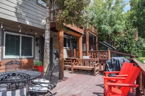 Une terrasse en bois aménagée avec du mobilier d’extérieur, notamment une table, des chaises et un banc.