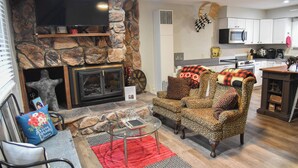 Una sala de estar con chimenea de piedra, televisor, sofá y mesa de centro.