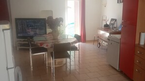 Una cocina con una mesa de comedor, sillas, un refrigerador y un armario.