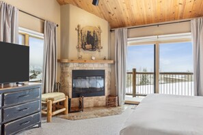 A bedroom with a large bed, a fireplace, a TV, and a balcony with a view. - Outpost: Harvest Dance 3198 - Teton Views (Jackson)