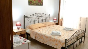Ein Schlafzimmer mit einem Bett, zwei Nachttischlampen, einem Nachttisch, einem kleinen Tisch mit Lampe und einem Bild an der Wand.