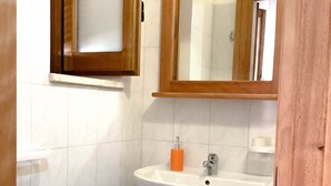 Ein Badezimmer mit Waschbecken, Spiegel und blauem Mülleimer.