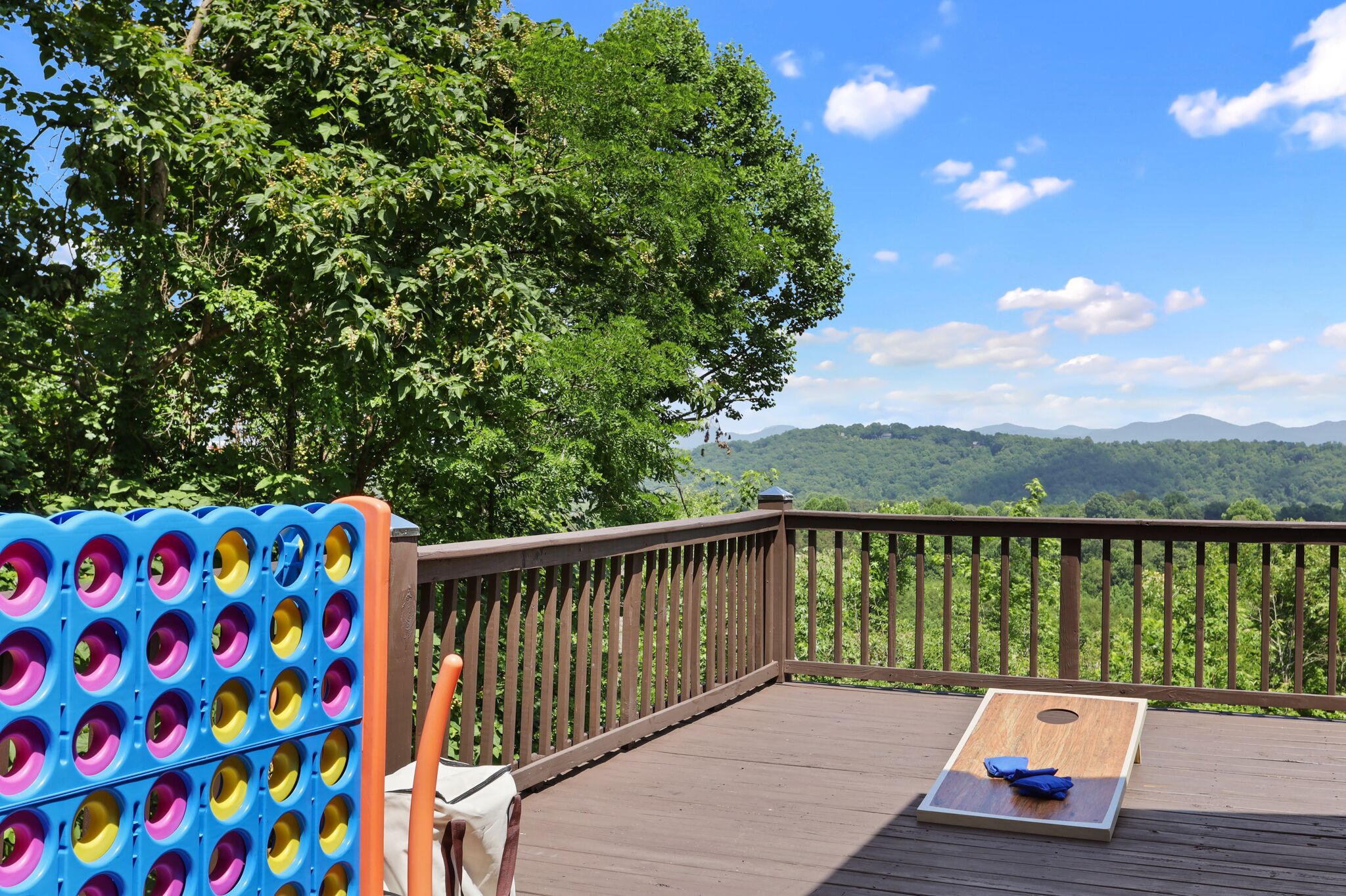 A wooden deck with a view of mountains, a blue and yellow game board, and a wooden table.
