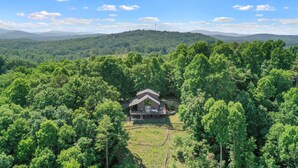 A house surrounded by dense forest with a clear view of distant mountains. - Mountain View Luxury Lodge! Movie Theater, Hot Tub, Fire Pit! (Blue Ridge)