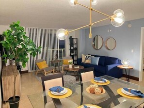 Relax in this stylish living room with a glass dining table, sofa, and unique light fixture.