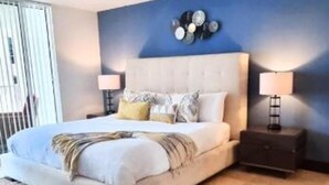 A bedroom with a large bed, two bedside tables, a wall clock, and a window with blinds. - Condo in Brickell the best Miami. Free parking (Brickell)